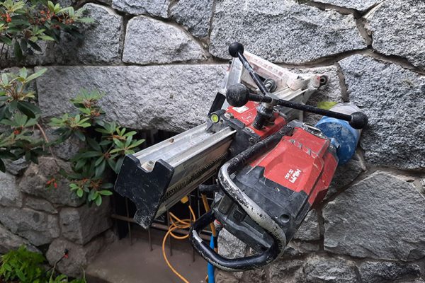 Core drill rig working on a stone wall